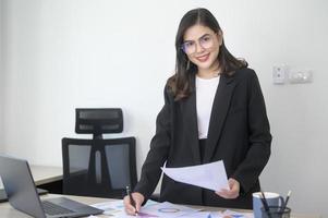 joven y hermosa mujer de negocios que trabaja en una laptop con documentos en una oficina moderna foto