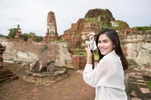 joven hermosa mujer viajando y tomando fotos en el parque histórico tailandés, vacaciones y concepto de turismo cultural.