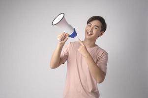 joven sonriente sosteniendo megáfono sobre estudio de fondo blanco. foto