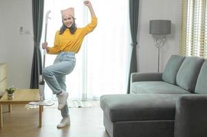 Young happy woman mopping and vacuum the floor in living room. photo