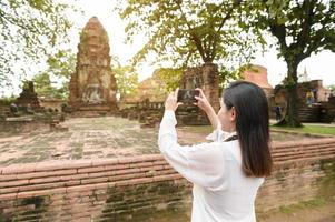 young beautiful woman traveling and taking photo at thai historical Park, Holidays and cultural tourism concept.