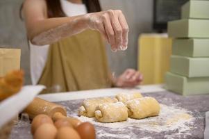 El primer plano de una joven hermosa mujer está horneando en su negocio de cocina, panadería y cafetería. foto