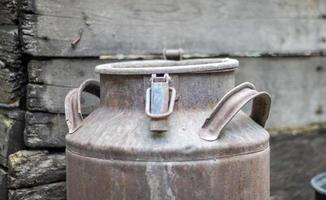 One old rusty metal can in the countryside. Container for transporting liquids, milk or liquid fuels with multiple handles. Milk bank of a cylindrical form with a wide mouth. Bottle with sealed cap. photo