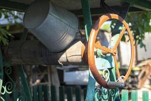 A well with a bucket in a European village. Sunny day. Metal bucket for a water well. Detail of a well with a tin bucket in the countryside. Decorating the garden with vintage items. photo