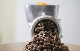Minced meat in a manual mechanical meat grinder. Fresh boiled meat is ground with an old metal meat grinder, close-up in the kitchen. photo