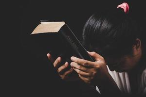 la mano de una mujer cristiana en la sagrada biblia es orar y adorar gracias a dios en la iglesia con antecedentes negros, concepto de fe, espiritualidad y religión foto