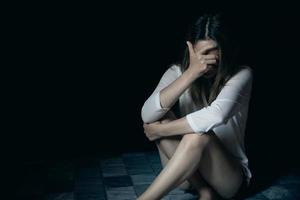 Young person woman sad, stress and loneliness sitting in dark room, Unhappy and crying teenage girl from domestic violence, An adult female expresses feelings of despair, anxiety from harassment. photo