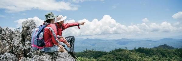 Young tourist couple watching spectacular mountain scenery in high mountains. man and woman hiker on top rock. A couple of travelers in love. People greet the dawn. Lovers travel. Copy space photo