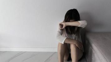 mujer joven triste, estresada y solitaria sentada en una habitación oscura, adolescente infeliz y llorando por violencia doméstica, una mujer adulta expresa sentimientos de desesperación, ansiedad por el acoso. foto