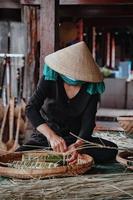 foco anciana con vestido vietnamita tradicional ao ba ba haciendo, envolviendo pastel tet, el año nuevo lunar vietnamita comida tet al aire libre con las manos. foto