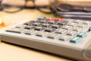 equipo de calculadora de cierre para ingresos, gastos, cálculo en mesa de madera foto