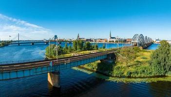 un puente sobre el río daugava en riga con un tren pasando. foto