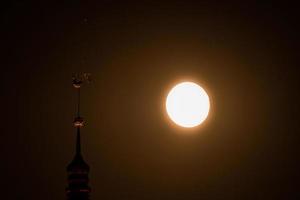 hermosa luna llena sobre el casco antiguo de riga con cúpulas catedral gallo dorado visible foto