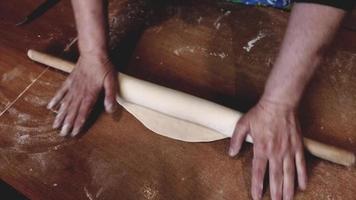 rolling out the dough on the table with a large rolling pin video