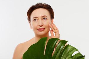 Beauty middle age woman macro face portrait. Spa and anti aging concept and leaf Isolated on white background. Plastic surgery and collagen face injections.Wrinkles and menopause. Mock up. Copy space. photo