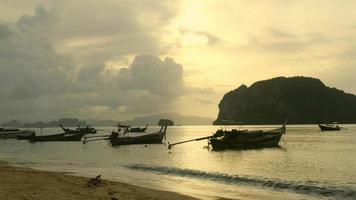 muitos barcos de pesca no mar com fundo do céu do nascer do sol na ásia. cais dos aldeões na ilha sul da tailândia. video