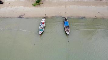 vista aérea de drones de barcos de pesca na costa durante a maré baixa. vista superior de muitos barcos de pesca de cauda longa tailandesa nas ilhas tropicais. muito barco de cauda longa no mar