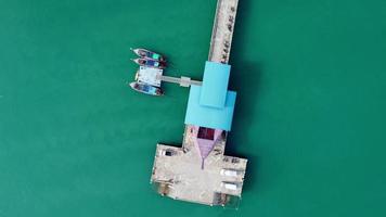 vista aérea de um drone de um cais em um mar tropical. muitos barcos de pesca tradicionais tailandeses de cauda longa no mar. video
