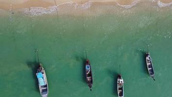 vue aérienne depuis des drones de bateaux de pêche sur le rivage à marée basse. vue de dessus de nombreux bateaux de pêche traditionnels thaïlandais à longue queue dans les îles tropicales. beaucoup de bateau à longue queue sur la mer video