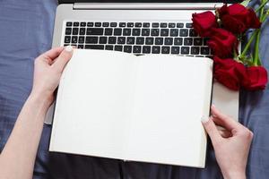 Hands, computer keyboard, bed top view. Workplace background, work at home, notepad and flowers photo
