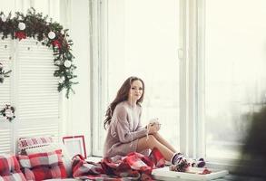 happy woman sitting on windowsill in Christmas holidays photo