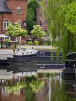 Narrowboat, trees and their reflections in the canal water in Castlefield, Manchester, UK photo