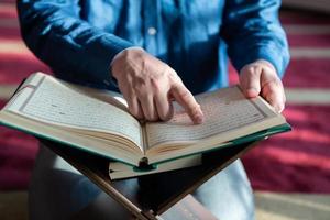 muslim man praying Allah alone inside the mosque and reading islamic holly book photo