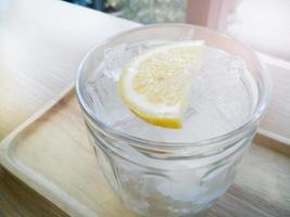 The ice lemon soda on wood table window light for background. photo
