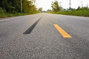 A close-up low-angle view. A long line of black rubber tires stopping violently against the paved road surface. photo