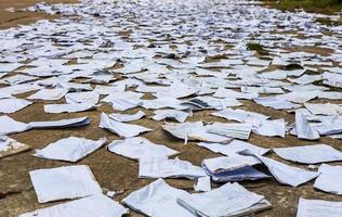 Scraps of old square paper from many notebooks are scattered on the concrete floor to dry. photo