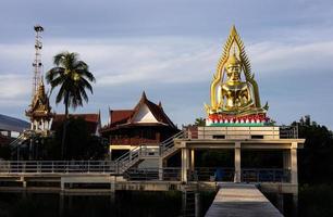 A view of a large meditating golden Buddha statue enshrined on a concrete hall structure. photo