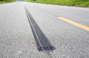 A close-up low-angle view, a long line of black tires stopping violently against the paved road surface. photo