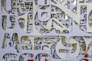 Fragmented backgrounds of white plates, which have been stenciled in letters of various sizes. photo