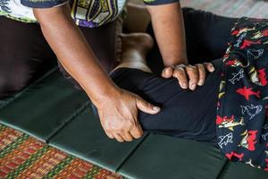 Close-up view of both hands of an elderly Thai female masseuse squeezing and bending the legs. photo