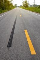 A close-up low-angle view. A long line of black rubber tires stopping violently against the paved road surface. photo