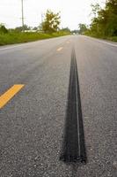 A close-up low-angle view. A long line of black rubber tires stopping violently against the paved road surface. photo