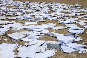 Scraps of old square paper from many notebooks are scattered on the concrete floor to dry. photo