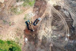 Aerial top view of excavator and dump trucks working at the construction site photo