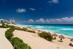 Umbrelas on a sandy beach with azure water on a sunny day near Cancun, Mexico photo