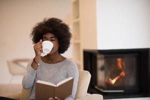 mujer negra leyendo un libro frente a la chimenea foto
