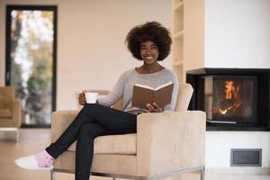 mujer negra leyendo un libro frente a la chimenea foto