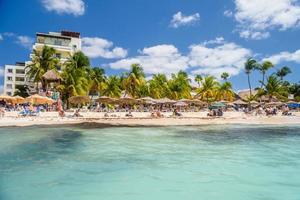 People sunbathing on the white sand beach with umbrellas, bungalow bar and cocos palms, turquoise caribbean sea, Isla Mujeres island, Caribbean Sea, Cancun, Yucatan, Mexico photo