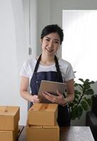 Portrait of Asian young woman SME working with a box at home the workplace.start-up small business owner, small business entrepreneur SME or freelance business online and delivery concept. photo