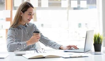 Beautiful young asian woman sitting at coffee shop using laptop. Happy young businesswoman sitting at table in cafe with tab top computer. photo