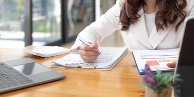 Business woman using calculator and laptop for do math finance on wooden desk in office and business working background, tax, accounting, statistics and analytic research concept photo