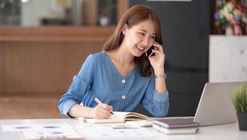 mujer de negocios asiática con traje formal en la oficina feliz y alegre durante el uso del teléfono inteligente y el trabajo foto