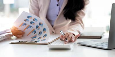 Close up Business woman using calculator and laptop for do math finance on wooden desk in office and business working background, tax, accounting, statistics and analytic research concept photo