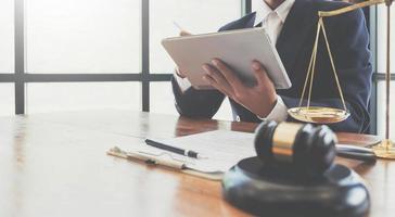 justice and law concept.Male judge in a courtroom the gavel,working with digital tablet  on wood table in office photo