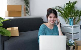 Closeup startup small business SME, Entrepreneur owner using smartphone or tablet taking receive and checking online purchase shopping order to preparing pack product box. Selling online ideas concept photo
