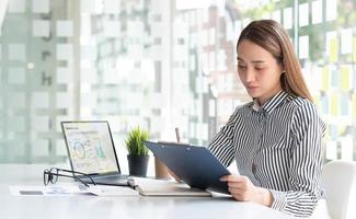 Young Asian businesswoman taking notes using a tablet at the modern office. photo